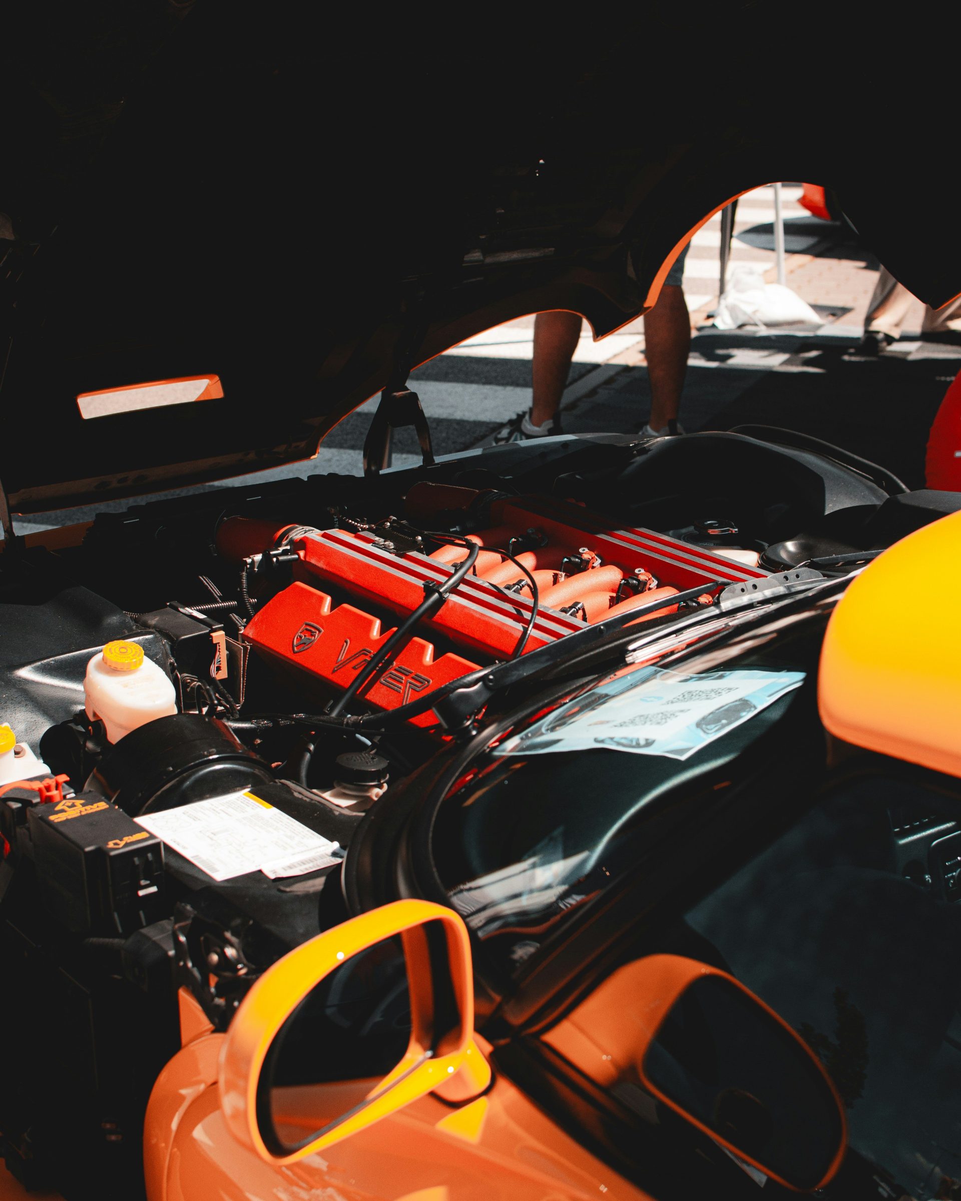 An open car hood reveals a powerful red engine.